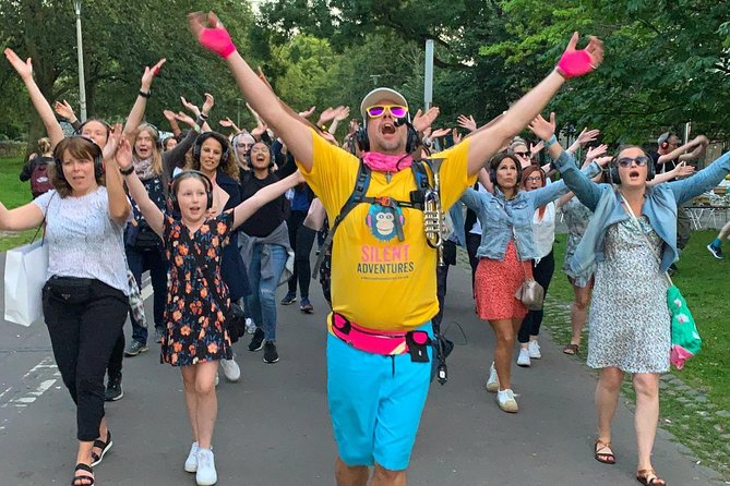 Tourists revel in joyous abandon on a guided silent disco tour, where headphones pulsate with infectious beats, transforming the city into a vibrant dancefloor beneath the starlit sky.